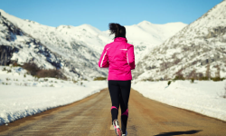 woman running down run in snow-capped mountains